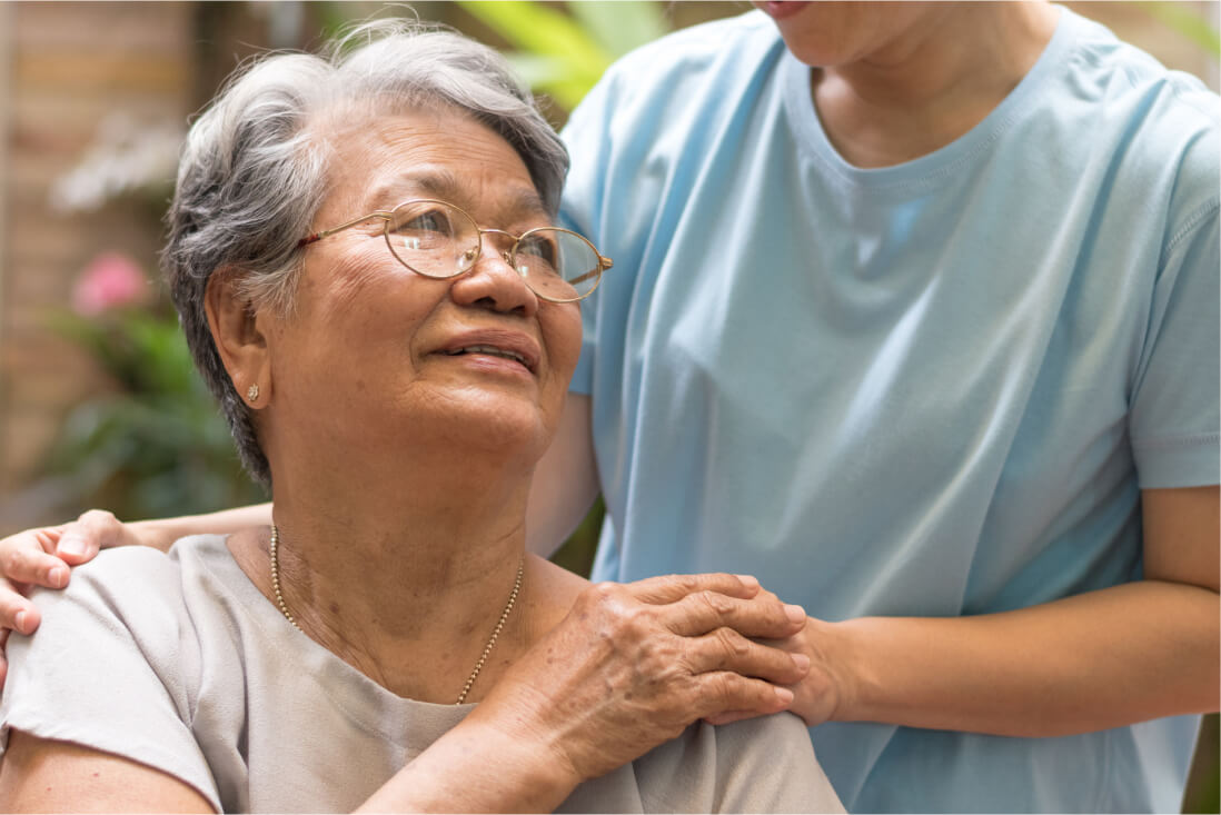 Elderly lady wearing glasses looking up at the caregiver